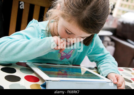 Horizontal portrait of a young girl playing games on a tablet. Stock Photo