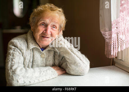 An elderly woman sitting dreamily by the window. Stock Photo