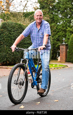 Vertical portrait of an elderly man riding his bike on the road. Stock Photo