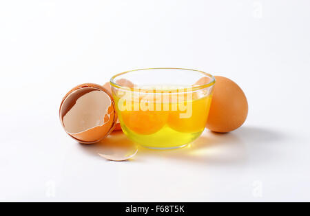 Fresh egg whites and yolks in glass bowl, one whole egg and empty eggshells Stock Photo