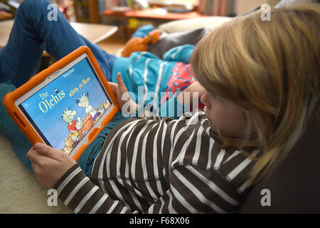 Oldenburg, Germany. 10th Nov, 2015. Eight-year-old Jonte plays the educational game 'Die Olchis' (The Olchis) on a tablet at his family's home in Oldenburg, Germany, 10 November 2015. Publishing companies are increasingly offering apps and educational games in addition to traditional storybooks. Photo: CARMEN JASPERSEN/dpa/Alamy Live News Stock Photo