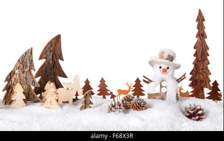 Wooden decoration arranged as a cute winter scene with a snowman, conifer trees, animals and snow, isolated on white background Stock Photo