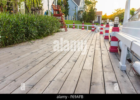 Empty wooden jetty on the lake shore with island and yachts in the background Stock Photo