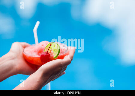 Tasty cocktail in female hands background turquoise sea Stock Photo