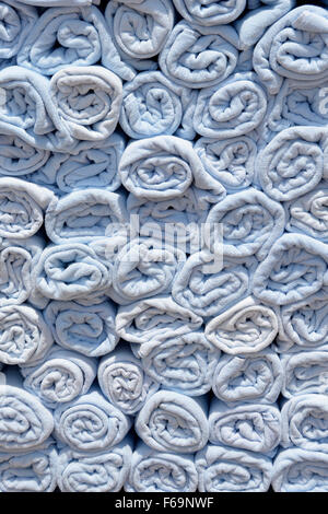 Abstract background end view close up of blue rolled up towel in stacks beside pool awaiting use by cruise ship passengers to place on sun loungers Stock Photo