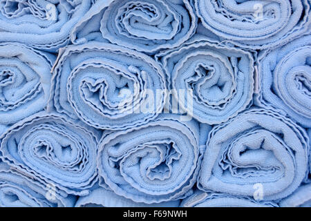 Abstract background end view close up of blue rolled up towels in stacks beside pool awaiting use by cruise ship passengers to place on sun loungers Stock Photo