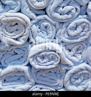 Abstract background end view close up of blue rolled up towel in stacks beside pool awaiting use by cruise ship passengers to place on sun loungers Stock Photo