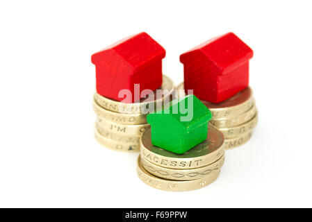 British Sterling one pound coins and a wood houses isolated on a white background with copy space and reflection Stock Photo