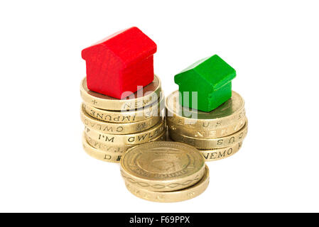 British Sterling one pound coins and a wood houses isolated on a white background with copy space and reflection Stock Photo
