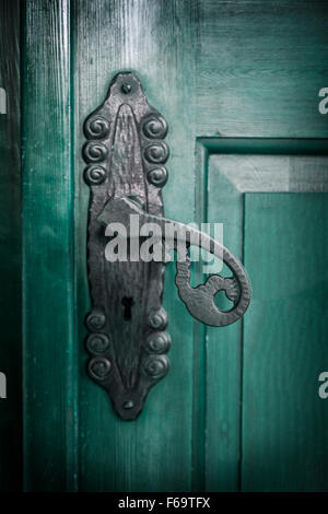 Image of a cast iron door handle on a green door. Stock Photo