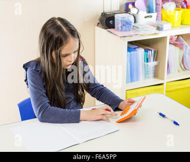 Asian American schoolgirl in class, using calculator Stock Photo