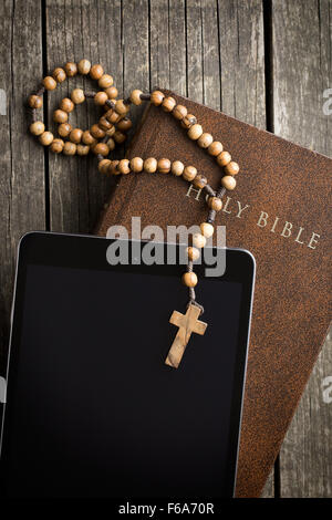 wooden rosary beads with computer tablet on old wooden table Stock Photo