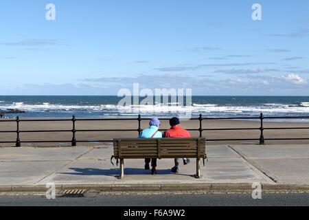 Elderly couple sitting on seafront bench in Scarborough Yorkshire Stock Photo