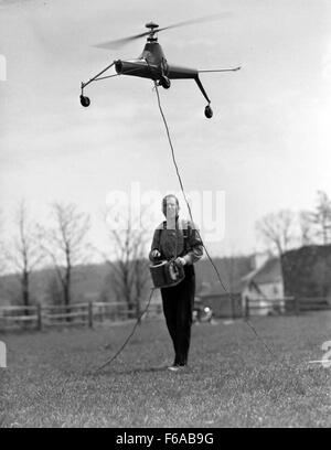 A remote-controlled model helicopter captured in flight in Pennsylvania. This small-scale aircraft is an example of hobbyist aerodynamics and radio-controlled technology in the mid-20th century. Stock Photo