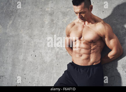 Close up image of male in shorts relaxing after workout on grey background. Muscular male body with sweat. Image with copyspace Stock Photo