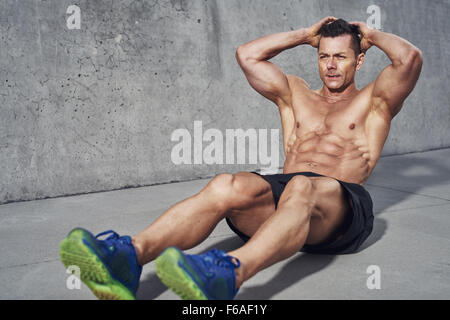 Male fitness model doing sit ups and crunches exercising abdominal muscles, six pack visible wearing no shirt Stock Photo