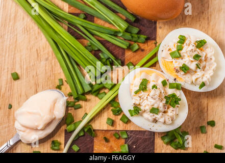 Two halves of boiled eggs with mayonnaise and sliced chive prepared on cutting Stock Photo