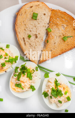 Boiled eggs with mayonnaise and sliced chive on plate and toasted bread arranged in heart shape Stock Photo