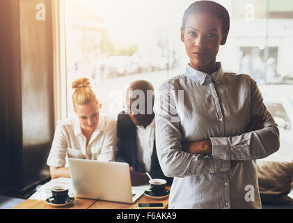 Confident black business woman standing in front of colleagues