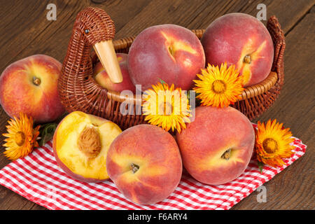 peaches in vintage basket on checkered red tablecloth-autumn still life Stock Photo