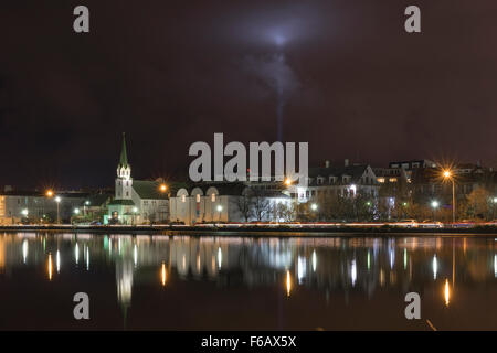 Night scene of Tjörnin lake in Reykjavik, Iceland, featuring the John Lenon & Oyko Ono Peace light piercing the clouds behind. Stock Photo