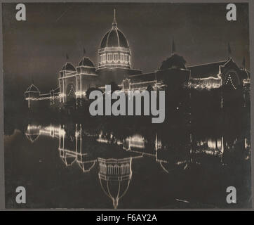 This historical photograph of the Melbourne Exhibition Building, taken in 1901, showcases the iconic structure illuminated at night, with a serene lake in the foreground. Stock Photo
