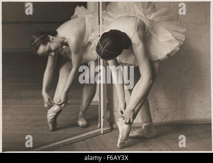 This photograph captures Rachel Cameron adjusting her ballet shoes, a moment of concentration before performance. The image focuses on the graceful movements associated with ballet and the artistry involved in preparing for a dance performance. Stock Photo