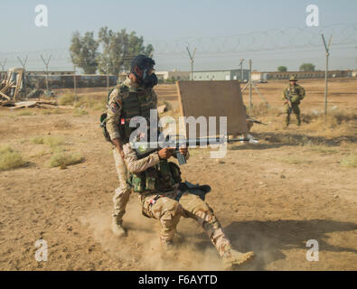 An Iraqi soldier assigned to the 71st Iraqi Army Brigade practices dragging casualty to cover while under fire during patrol exercise at Camp Taji, Iraq, Oct. 15, 2015. Iraqi soldiers performed basic drills while wearing a protective mask in order to simulate the vigorous environment created by a biochemical attack. Participating in this type of training at the Camp Taji building partner capacity site will prepare the soldiers for potential biochemical attacks when fighting against the Islamic State of Iraq and the Levant. (U.S. Army photo by Spc. William Marlow/Released) Stock Photo