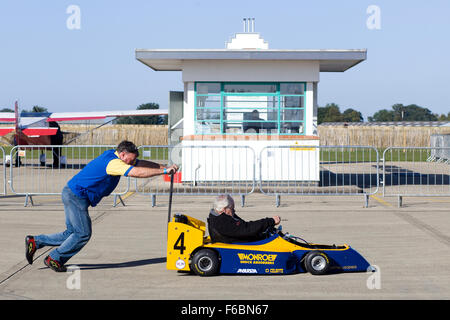 Man pushing a go cart onto a race track Stock Photo