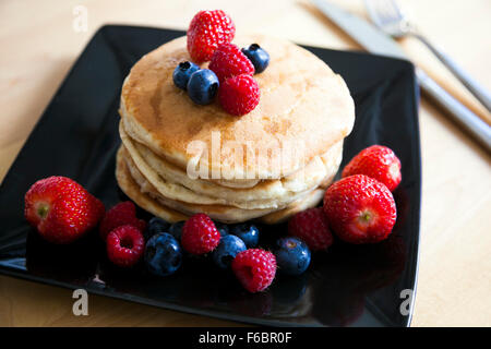 Fluffy pancakes with strawberries, blueberries, raspberries and maple syrup Stock Photo