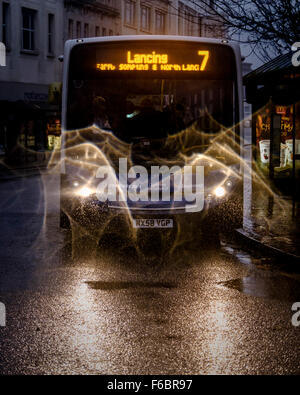 A stagecoach bus leaves a bus stop in the centre of Worthing on a dark rainy morning. The head lamps make interesting patterns in the fine rain. Picture by Julie Edwards Stock Photo