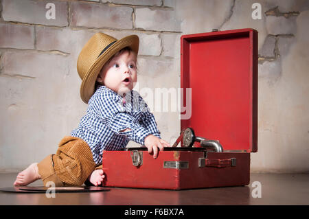 Funny baby boy in retro hat with vinyl record and gramophone Stock Photo
