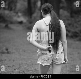 Country backwoods girl in old cut dungaree shorts in the woods, July 2014 Stock Photo
