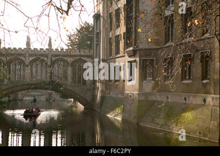 A punt passes below the bridge of Sighs in the University town of Cambridge, UK. Toursits often take the tour of the citys universities and here visitors enjoy the sights in the late afternoon sunshine.