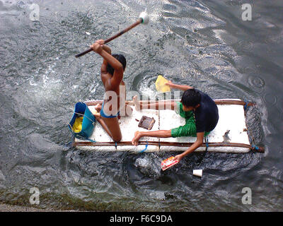 Filipino boys aboard an improvised raft paddle along the coast of Manila Bay in Navotas City, north of Manila, Philippines (Photo by Richard James Mendoza / Pacific Press) Stock Photo