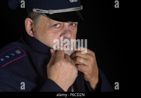 Portrait of older man in police uniform in low key Stock Photo