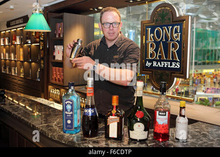 A man mixes a Singapore Sling cocktail at the Long Bar by Raffles at Changi International Airport in Singapore. Raffles is assoc Stock Photo