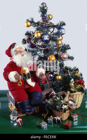 Festive New Year's, Christmas still life. Santa with a key sits on a chest with gifts near a Christmas fir-tree . Stock Photo