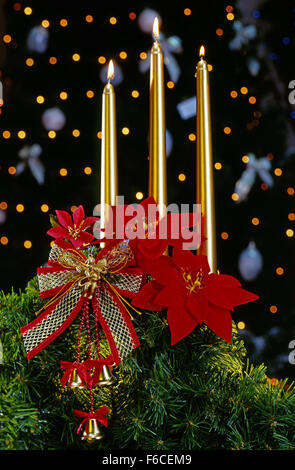 Festive New Year's, Christmas still life on a black background with red artificial flowers and three gold candles. vertical Stock Photo