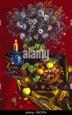 Festive New Year's, Christmas still life with a winter bouquet of flowers, a candlestick with a candle and fruit with nuts. Stock Photo