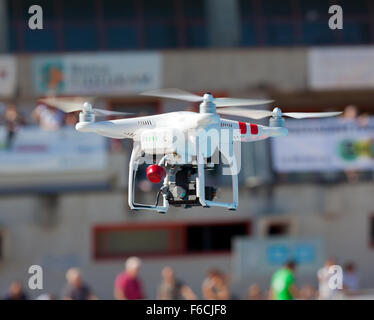 White drone quadcopter in flight with small camcorder. Stock Photo