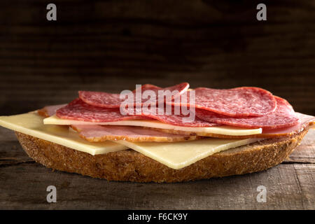 Open sandwich with ham, salami and cheese on wooden background Stock Photo