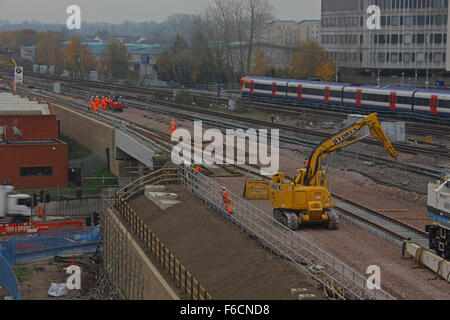 Showing track machinery and workers at work along the tracks with an electric train running on the far side of the construction. Stock Photo