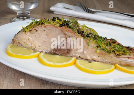 Baked piece of carp with lemon dill sauce on a plate Stock Photo