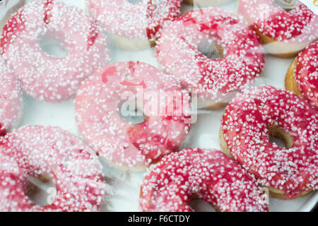 Close up of a box of pink iced doughnuts. Stock Photo