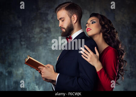Young elegant woman embracing man that reading book. Stock Photo