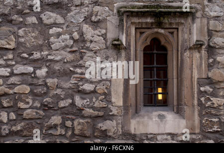 Monk's Window. A small window in an old wall of an abbey in the United Kingdom. A lamp burns inside. Stock Photo
