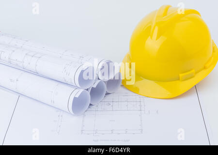 Yellow safety helmet and Scrolls of engineering drawings. Stock Photo