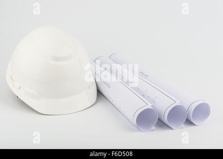 White safety helmet and Scrolls of engineering drawings. Stock Photo