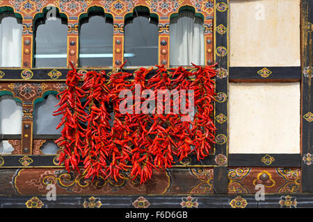 Red chili pepper pods hanging at a window for drying, Paro, Bhutan Stock Photo